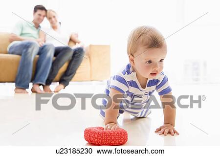 Stock Image - Couple in living room with baby smiling. Fotosearch
