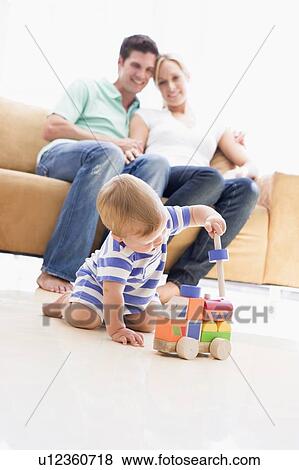 Couple in living room with baby smiling View Large Photo Image Stock Photo - Couple in living room with baby smiling. Fotosearch