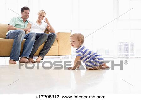 Couple in living room with baby smiling View Large Photo Image Stock Photo - Couple in living room with baby smiling. Fotosearch