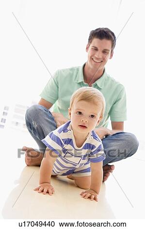 Stock Image - Father and baby indoors playing and smiling. Fotosearch