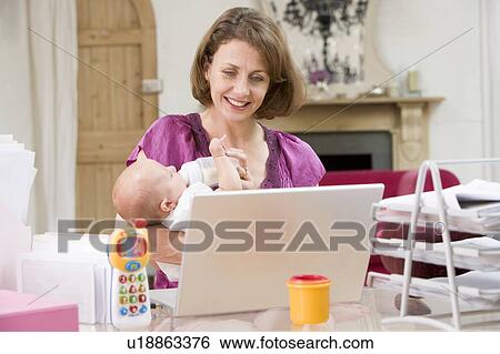 Stock Photograph - Mother and baby in home office with laptop. Fotosearch