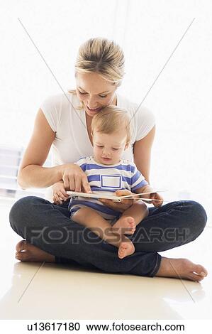 Mother and baby indoors reading book and smiling View Large Photo Image Stock Image - Mother and baby indoors reading book and smiling. Fotosearch