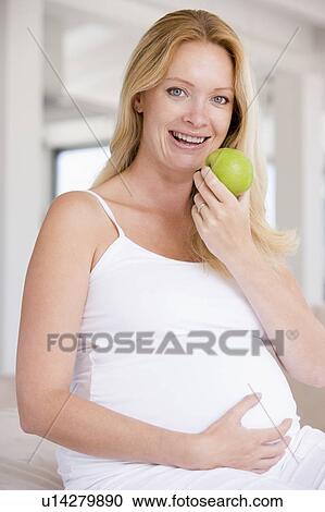 Pregnant woman eating apple and smiling View Large Photo Image Stock Image - Pregnant woman eating apple and smiling. Fotosearch