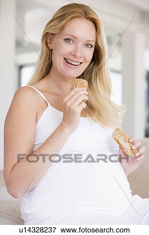 Stock Photo - Pregnant woman eating bread and smiling. Fotosearch