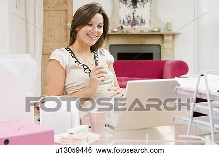 Pregnant woman in home office with laptop eating and smiling View Large Photo Image Stock Photograph - Pregnant woman in home office with laptop eating and smiling. Fotosearch