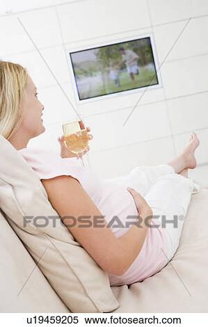 Pregnant woman watching television with glass of white wine View Large Photo Image Stock Photography - Pregnant woman watching television with glass of white wine. Fotosearch