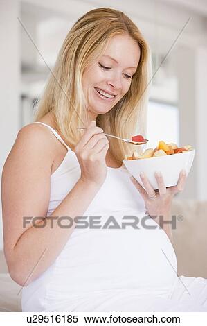 Stock Photography - Pregnant woman with bowl of fruit salad smiling. Fotosearch