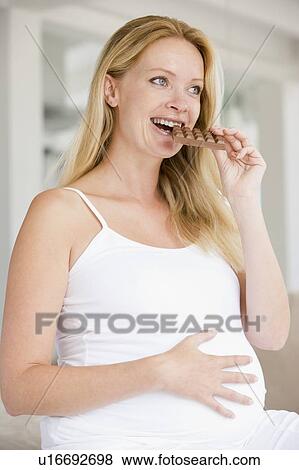 Stock Photo - Pregnant woman with chocolate smiling. Fotosearch