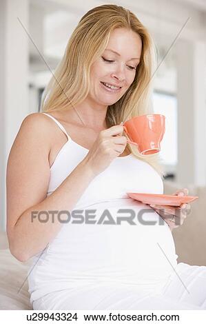Picture - Pregnant woman with cup of tea smiling. Fotosearch
