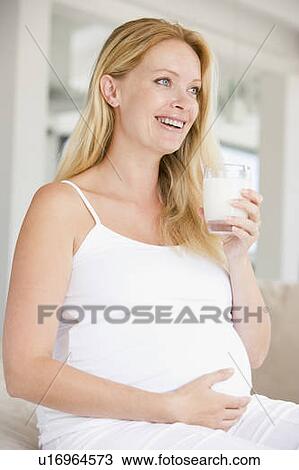 Stock Image - Pregnant woman with glass of milk smiling. Fotosearch