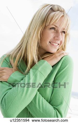 Picture - Blonde woman in a green sweater posing outdoors. Fotosearch
