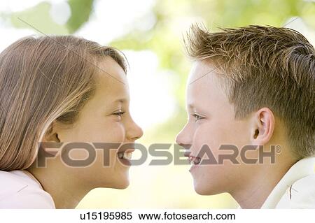 Brother and sister sitting outdoors staring at each other and smiling View Large Photo Image Stock Photography - Brother and sister sitting outdoors staring at each other and smiling. Fotosearch
