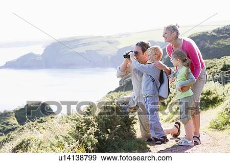 Family on cliffside path using binoculars and smiling View Large Photo Image Stock Photo - Family on cliffside path using binoculars and smiling. Fotosearch