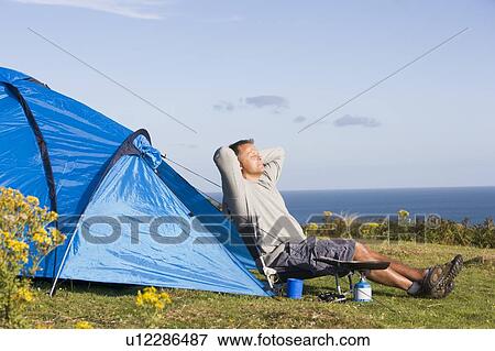 Stock Photo - Man camping outdoors and cooking. Fotosearch