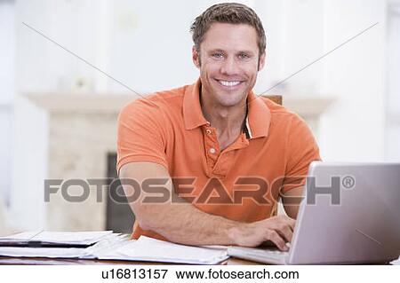 Man in dining room with laptop smiling View Large Photo Image Stock Photo - Man in dining room with laptop smiling. Fotosearch