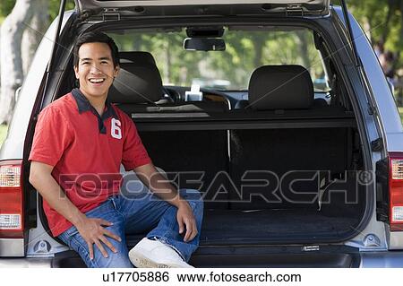 Stock Photograph - Man sitting in back of van smiling. Fotosearch