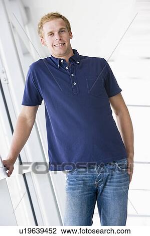 Stock Image - Man standing in corridor smiling. Fotosearch
