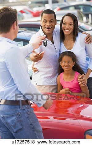 Stock Photo - Mother and father with young daughter shopping for a new car. Fotosearch