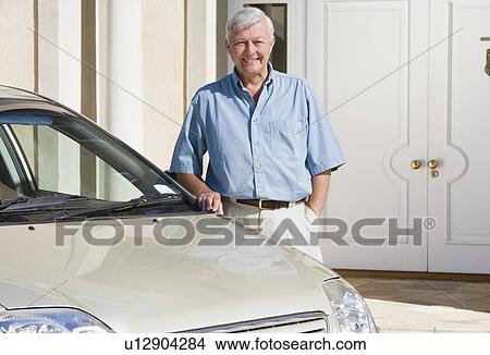 Picture - Senior man standing with his car outside his home. Fotosearch
