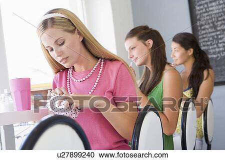 Stock Image - Three young women having a cold drink in a cafeteria. Fotosearch