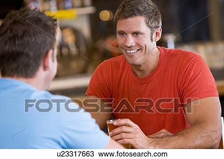 Stock Image - Two men having beer together. Fotosearch