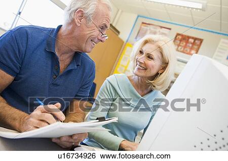 Stock Photograph - Two people at computer terminal with notepad. Fotosearch