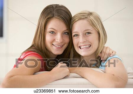 Stock Image - Two women in living room smiling. Fotosearch