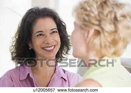 Stock Photo - Two women in living room smiling. Fotosearch