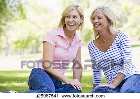 Two women sitting outdoors smiling View Large Photo Image Stock Image - Two women sitting outdoors smiling. Fotosearch