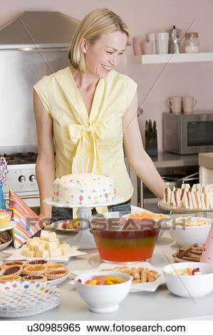 Woman at party standing by food table smiling View Large Photo Image Stock Photography - Woman at party standing by food table smiling. Fotosearch