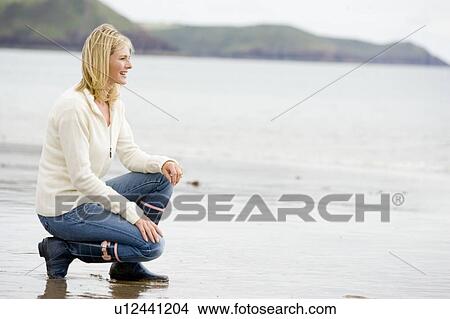 Woman crouching on beach smiling View Large Photo Image Picture - Woman crouching on beach smiling. Fotosearch