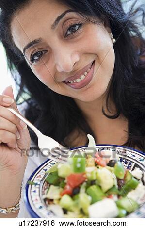 Stock Photograph - Woman holding bowl of salad and smiling (high key/selective focus). Fotosearch