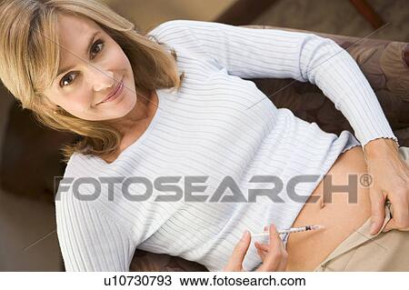 Stock Image - Woman injecting drugs to prepare for IVF treatment. Fotosearch