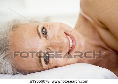 Stock Photo - Woman lying in bed smiling. Fotosearch