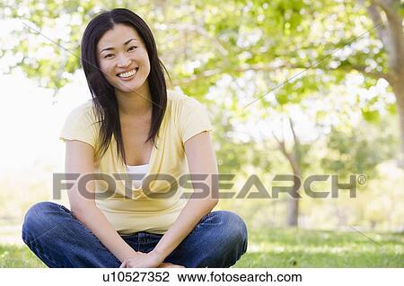 Stock Image - Woman sitting outdoors smiling. Fotosearch
