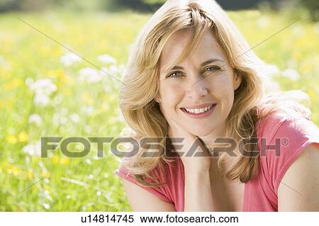 Stock Photography - Woman sitting outdoors smiling. Fotosearch