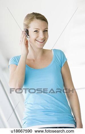 Woman standing in corridor wearing headset and smiling View Large Photo Image Stock Image - Woman standing in corridor wearing headset and smiling. Fotosearch