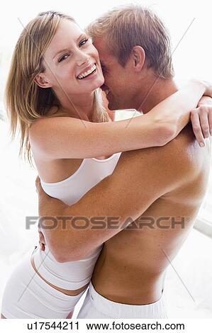 Stock Image - Couple bedroom embracing and smiling. Fotosearch