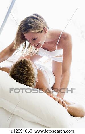 Couple lying in bed being playful and smiling View Large Photo Image Stock Image - Couple lying in bed being playful and smiling. Fotosearch