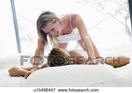 Couple lying in bed being playful and smiling View Large Photo Image Stock Photo - Couple lying in bed being playful and smiling. Fotosearch