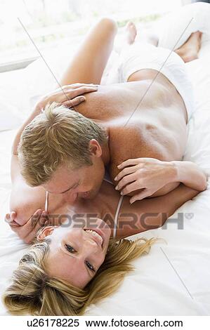 Stock Photography - Couple lying in bed embracing and smiling. Fotosearch