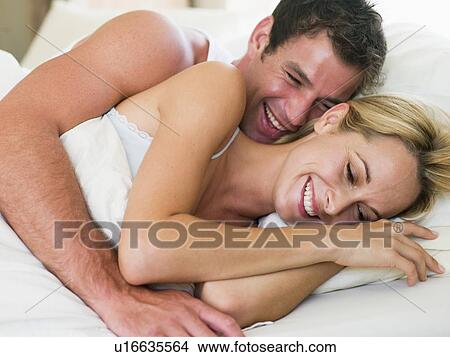 Couple lying in bed laughing View Large Photo Image Picture - Couple lying in bed laughing. Fotosearch