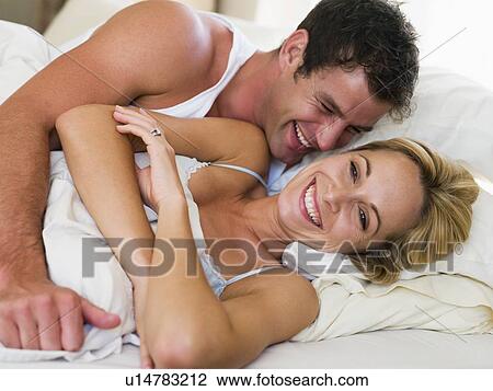 Couple lying in bed laughing View Large Photo Image Stock Image - Couple lying in bed laughing. Fotosearch