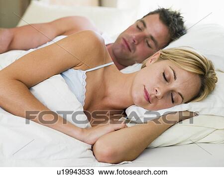 Stock Image - Couple lying in bed sleeping. Fotosearch