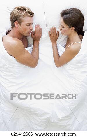 Stock Photograph - Couple lying in bed sleeping. Fotosearch