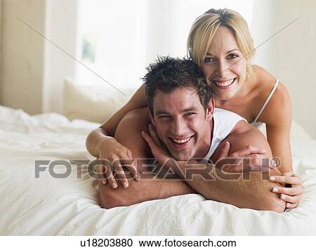 Couple lying in bed smiling View Large Photo Image Stock Image - Couple lying in bed smiling. Fotosearch