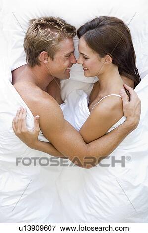 Stock Photo - Couple lying in bed smiling. Fotosearch