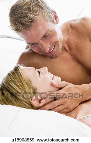 Stock Photo - Couple lying in bed smiling. Fotosearch