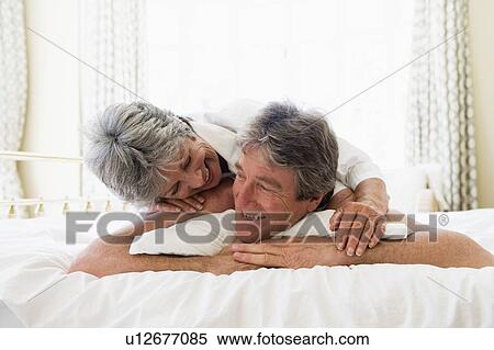 Couple relaxing in bedroom and smiling View Large Photo Image Stock Photography - Couple relaxing in bedroom and smiling. Fotosearch