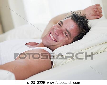 Man lying in bed laughing View Large Photo Image Stock Photo - Man lying in bed laughing. Fotosearch